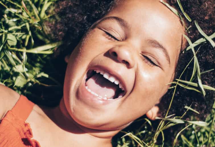 A happy child smiling and playing, promoting positive emotional health and well-being.